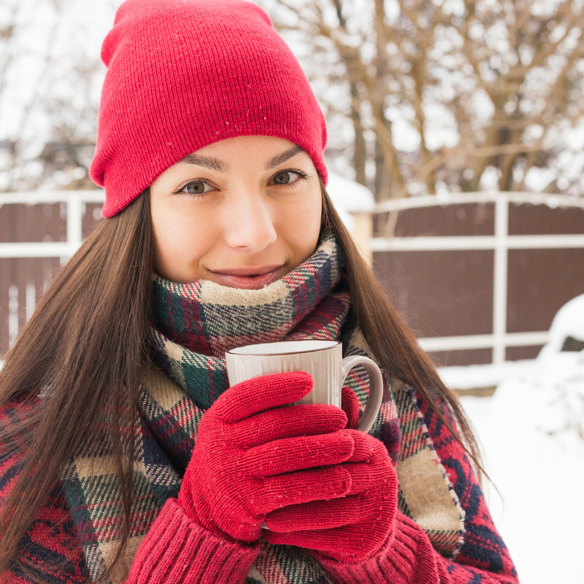 Beautiful happy smiling woman with a cup in the winter on the street